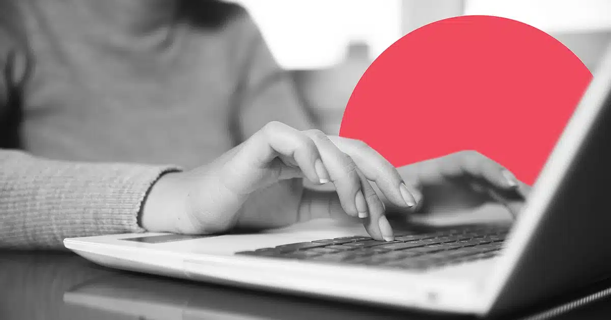 Closeup of a woman typing up an online review on a laptop.