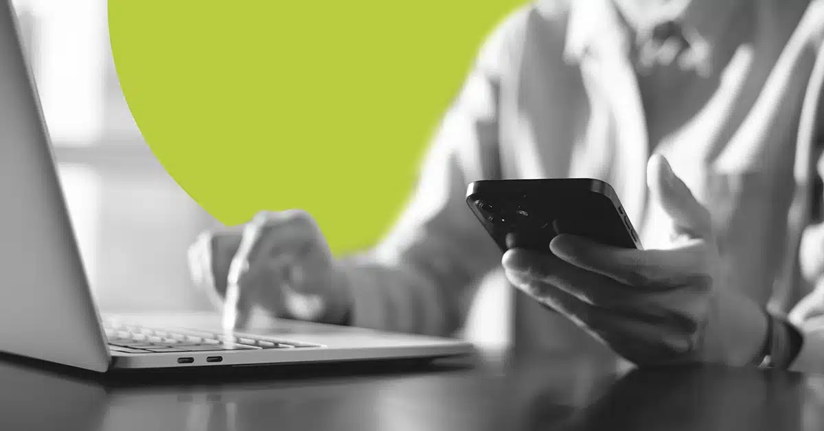 Closeup of a person using Google Fact Check on a mobile device while working on a laptop.