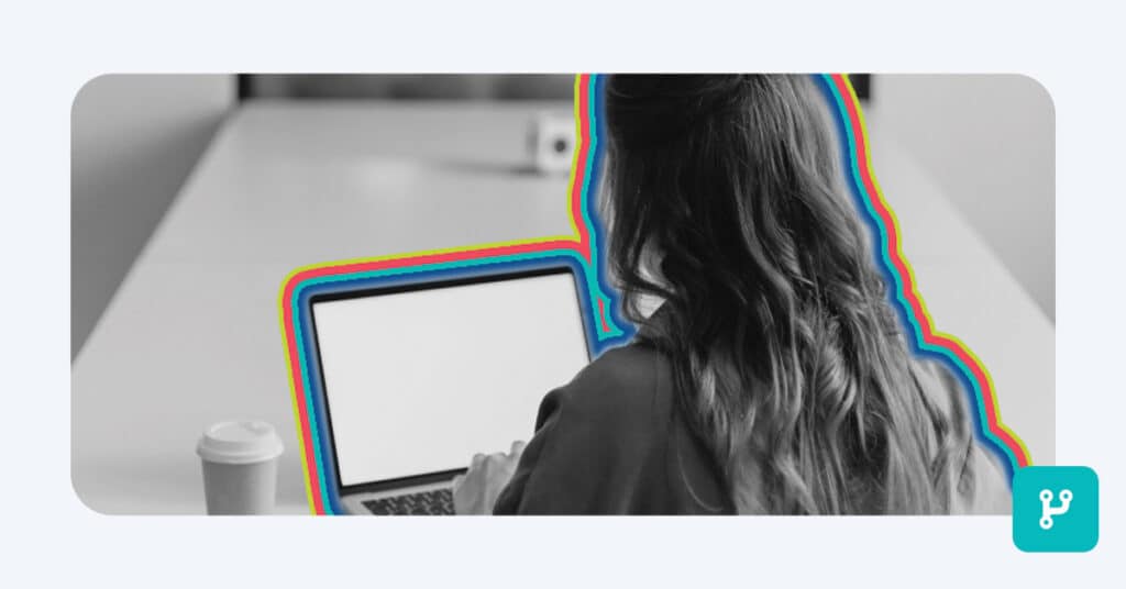 From behind, a young woman works on a laptop screen in a black and white image highlighted by rainbow bands of color to illustrate automated customer segmentation
