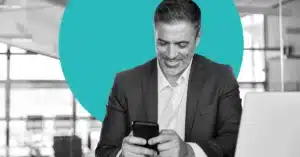 a businessman smiles at his mobile phone to illustrate customer retention marketing