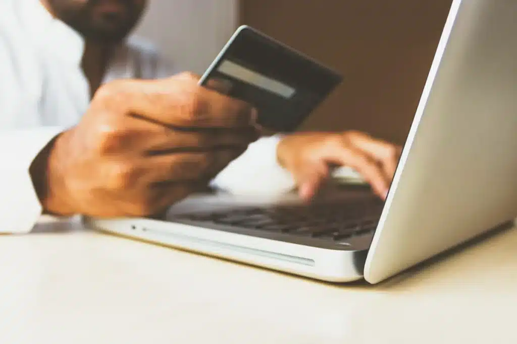 Closeup of a prospective customer using a credit card to complete a transaction with a laptop.