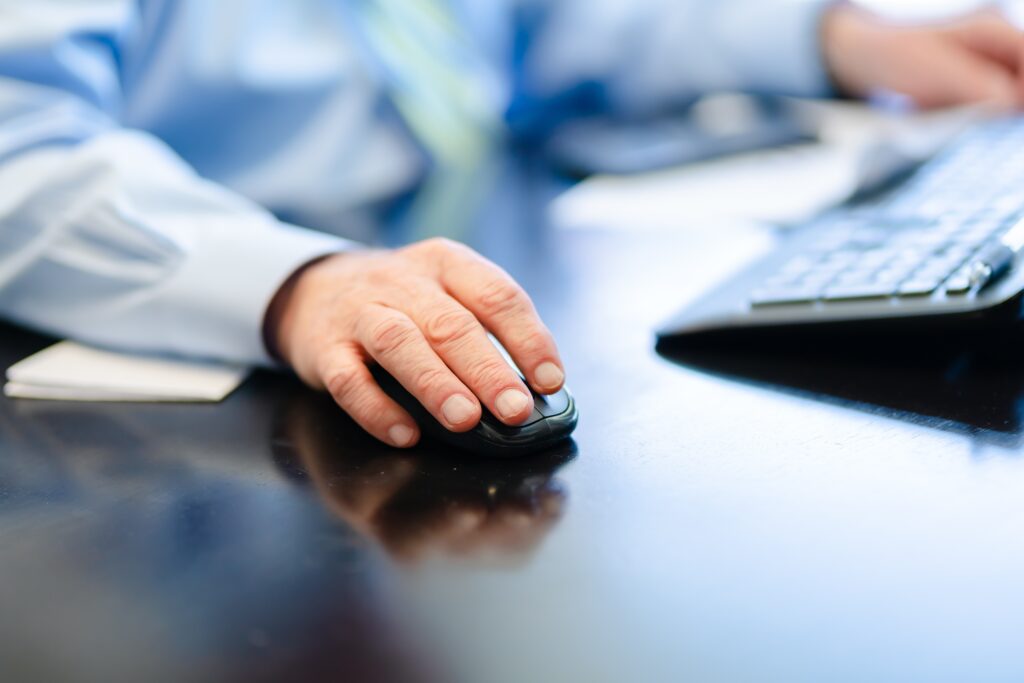 A hand clicks on a mouse at a computer desk to illustrate the idea of CTAs in marketing