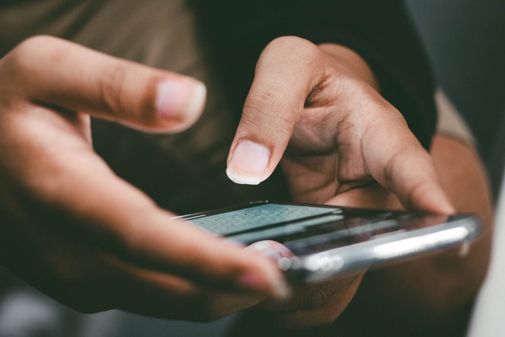 A closeup of brown hands holding a smartphone to illustrate SMS marketing examples.