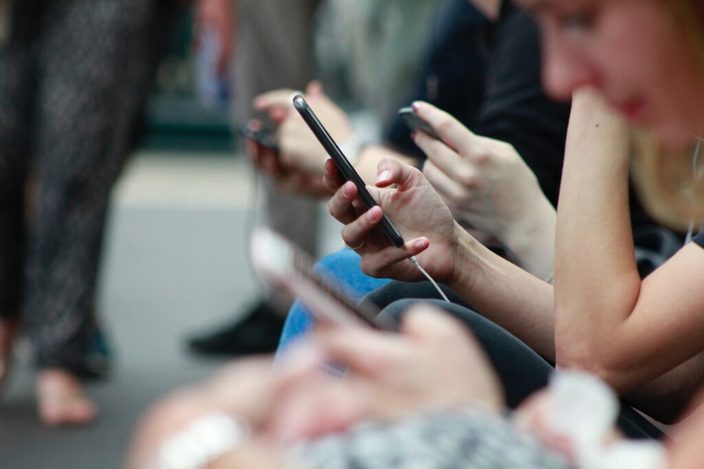 A close-up image of hands and phones as multiple people check their phone messages.