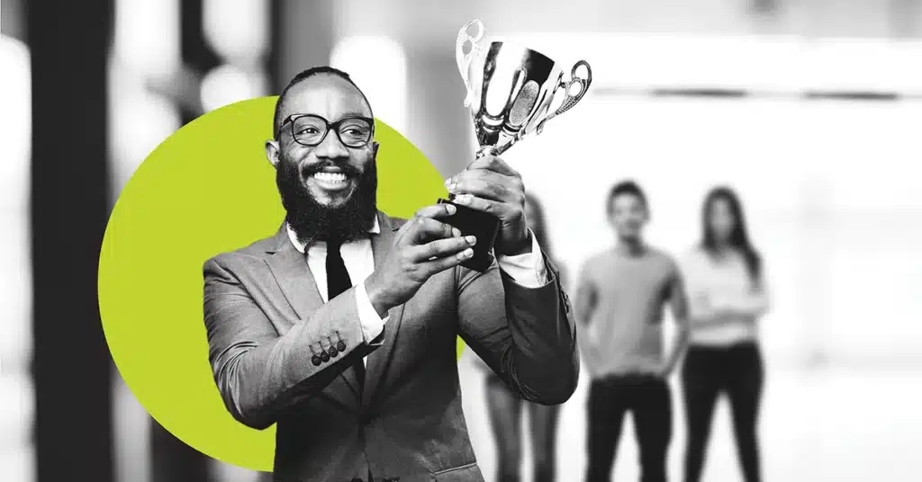 A business person holds a trophy with a big smile in black and white