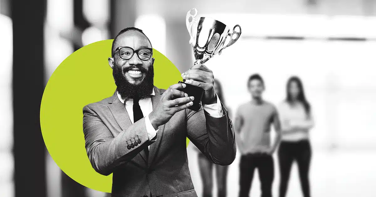 A business person holds a trophy with a big smile in black and white