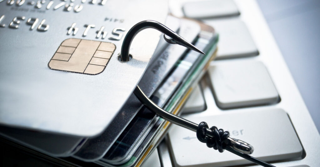Email authentication helps prevent phishing: piles of credit cards with a fish hook on computer keyboard