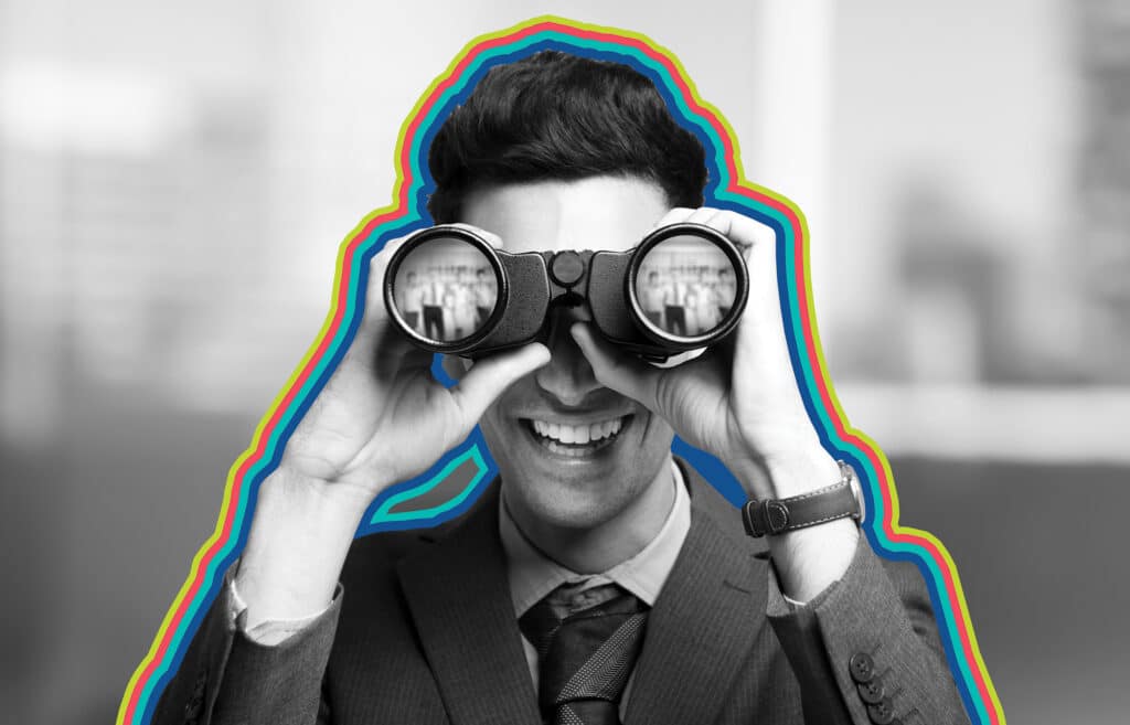 A man with binoculars searches for lower funnel keywords while smiling at the camera, in black and white, surrounded by rainbow outlines