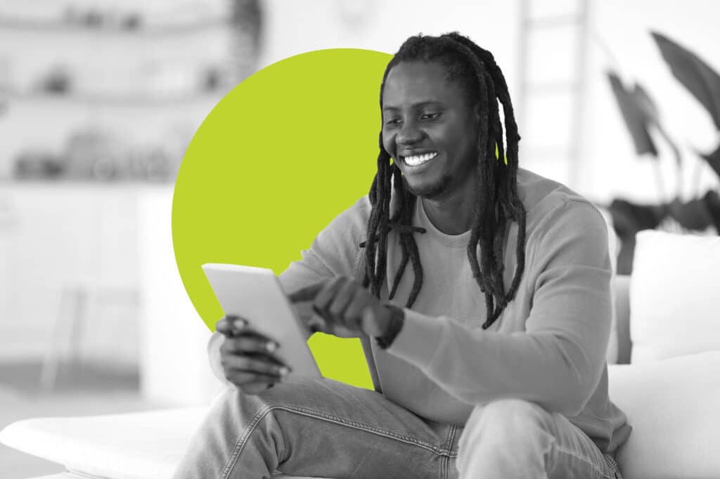 A young black man taps on a tablet to open a digital advertisement with a yellow branded bubble behind him.