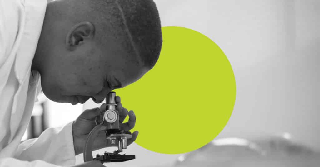 In black and white, a black doctor looks into a microscope to illustrate the idea of hipaa and marketing