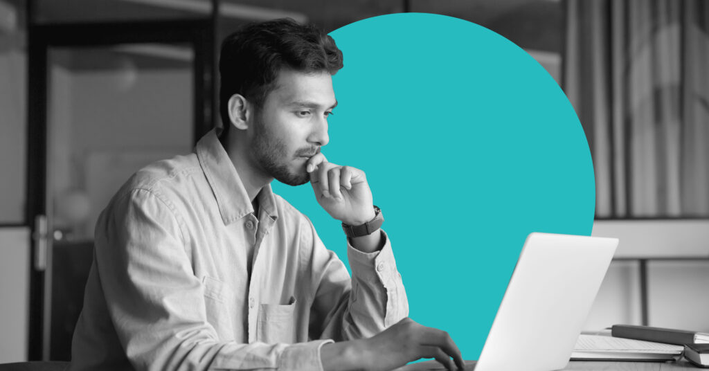 a man in profile works on a laptop with a pensive expression