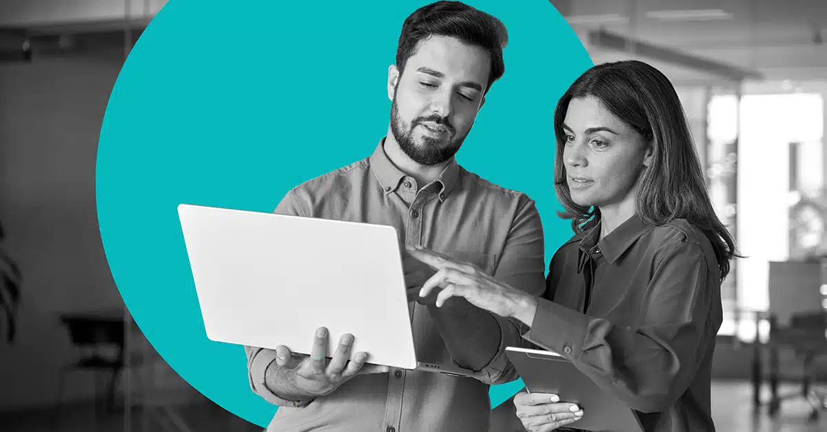 two professionals hold up a laptop and discuss the screen illustrating the idea of CCPA compliance requirements