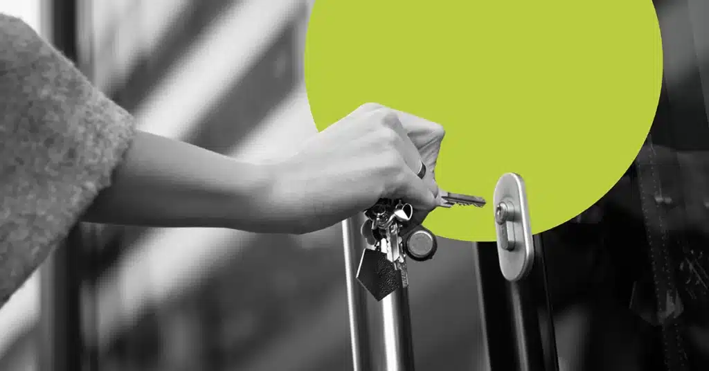a hand brings keys up to a lock in a black and white image