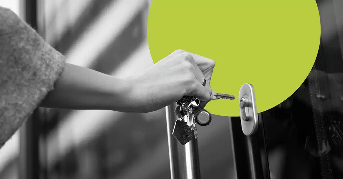 a hand brings keys up to a lock in a black and white image