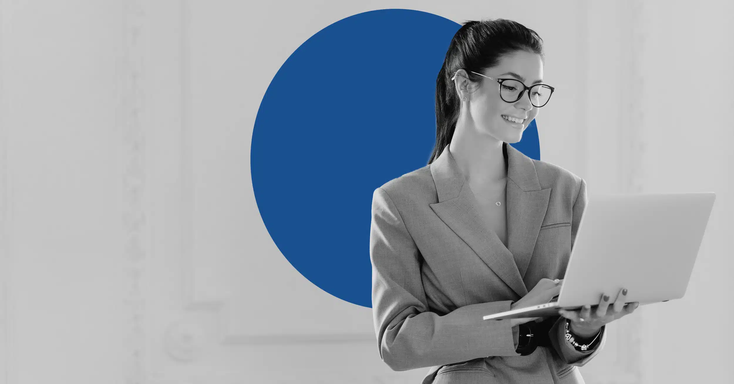a businesswoman holds a laptop while standing to illustrate credit union email marketing