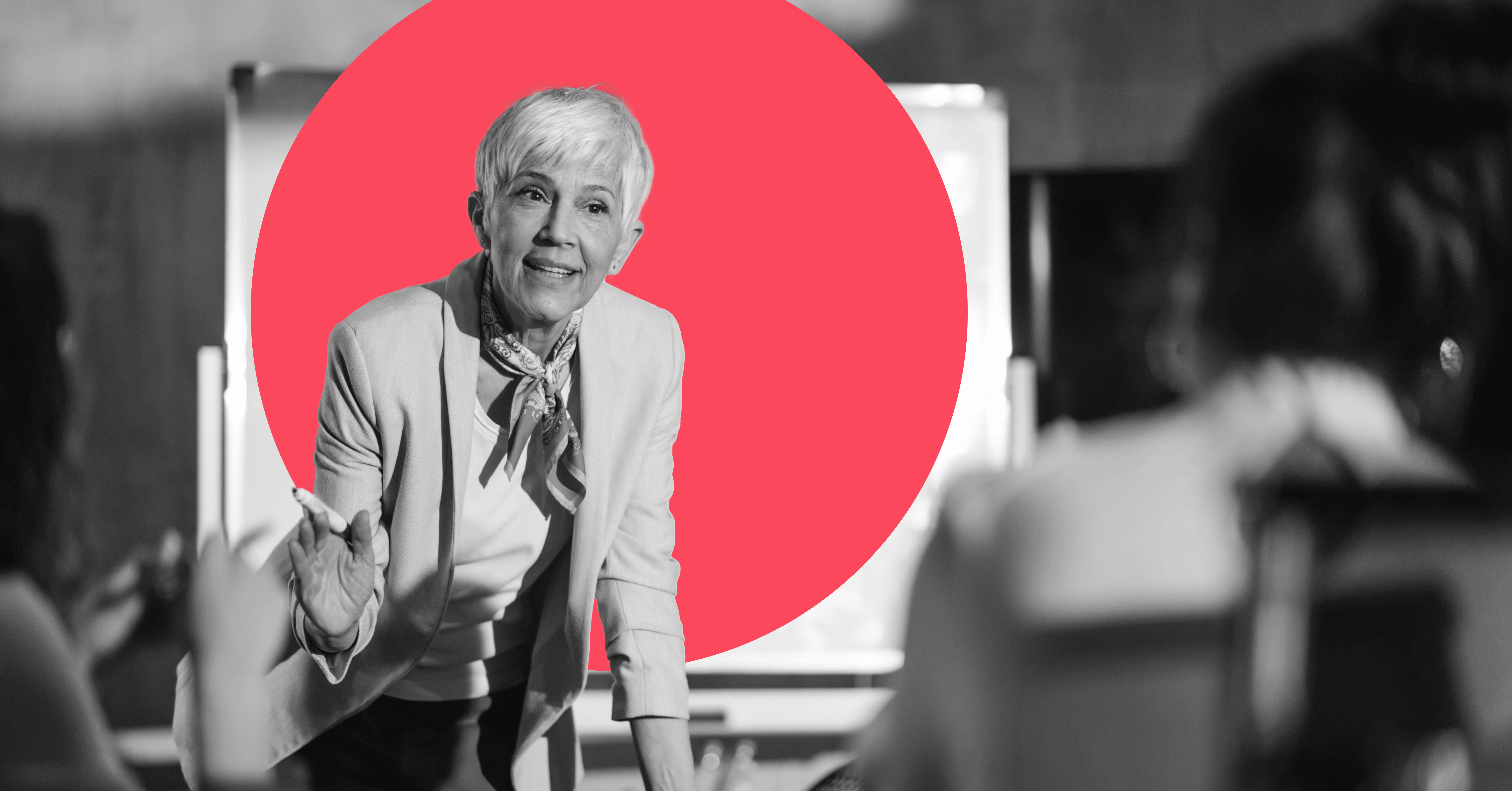 a businesswoman leans toward the camera over a table to make a point to someone in the foreground