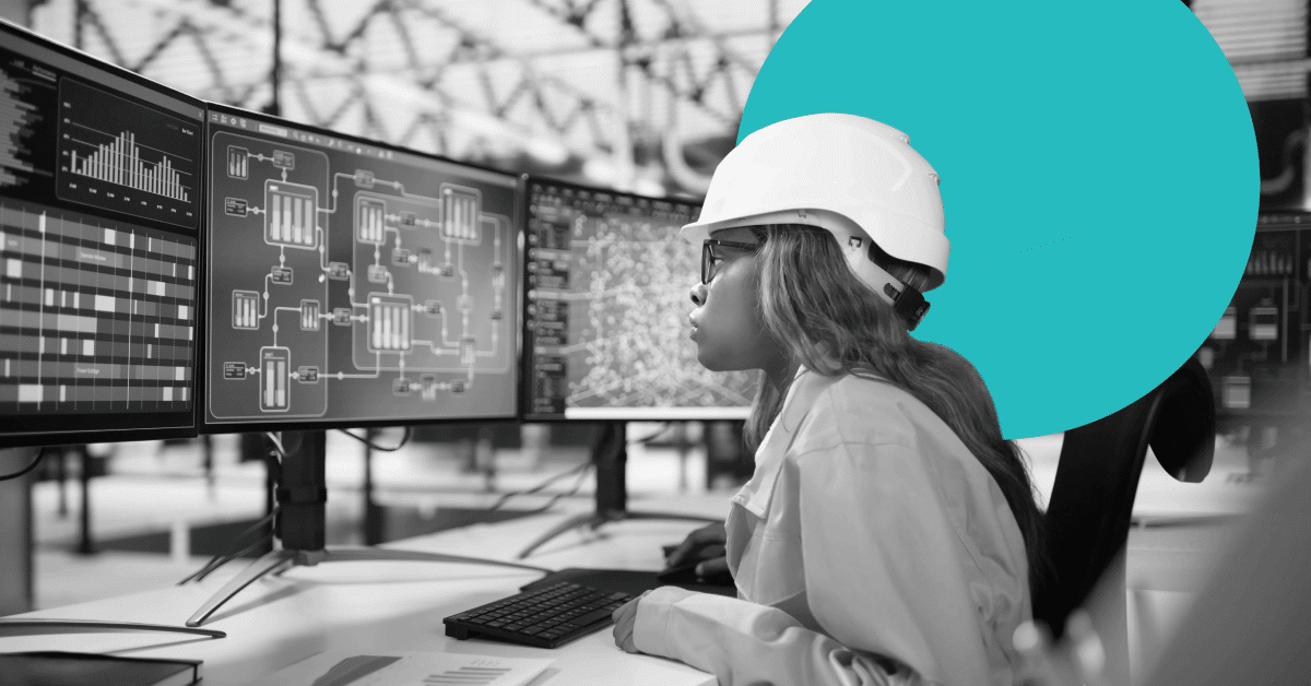 Woman in a hardhat reviewing manufacturing metrics on a computer screen.