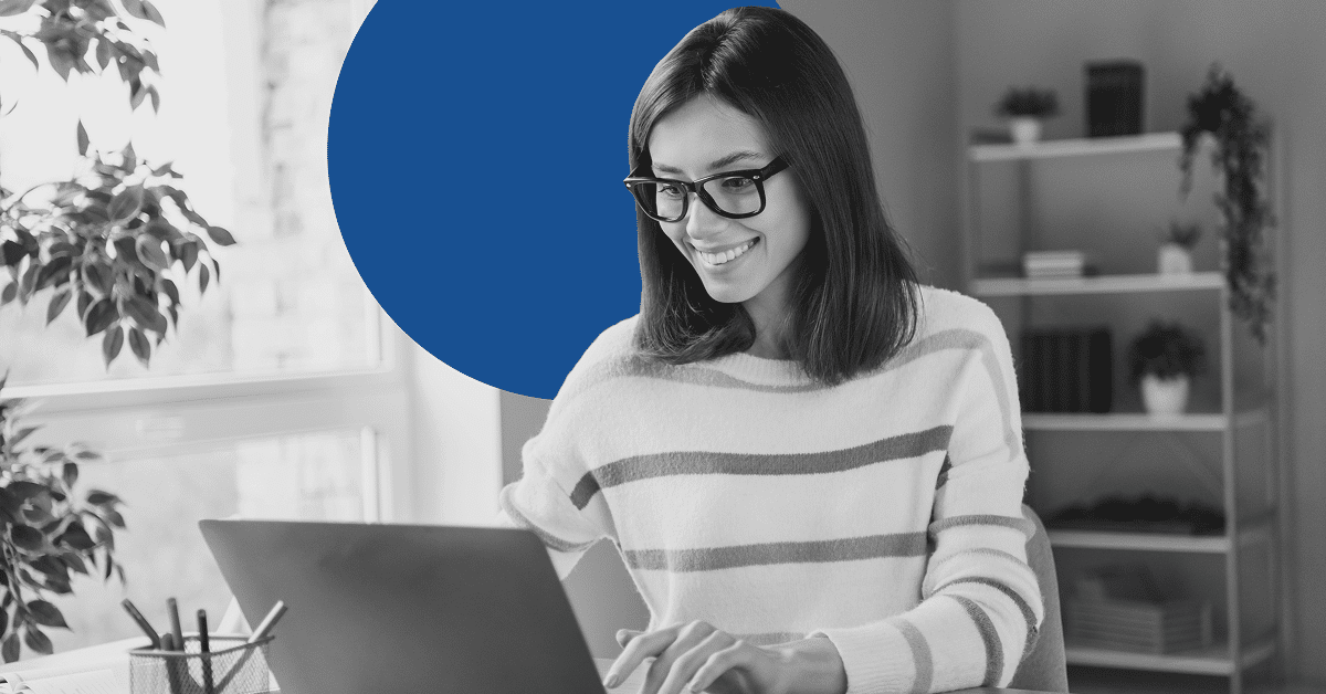 Smiling woman in glasses working on a laptop in a bright home office.