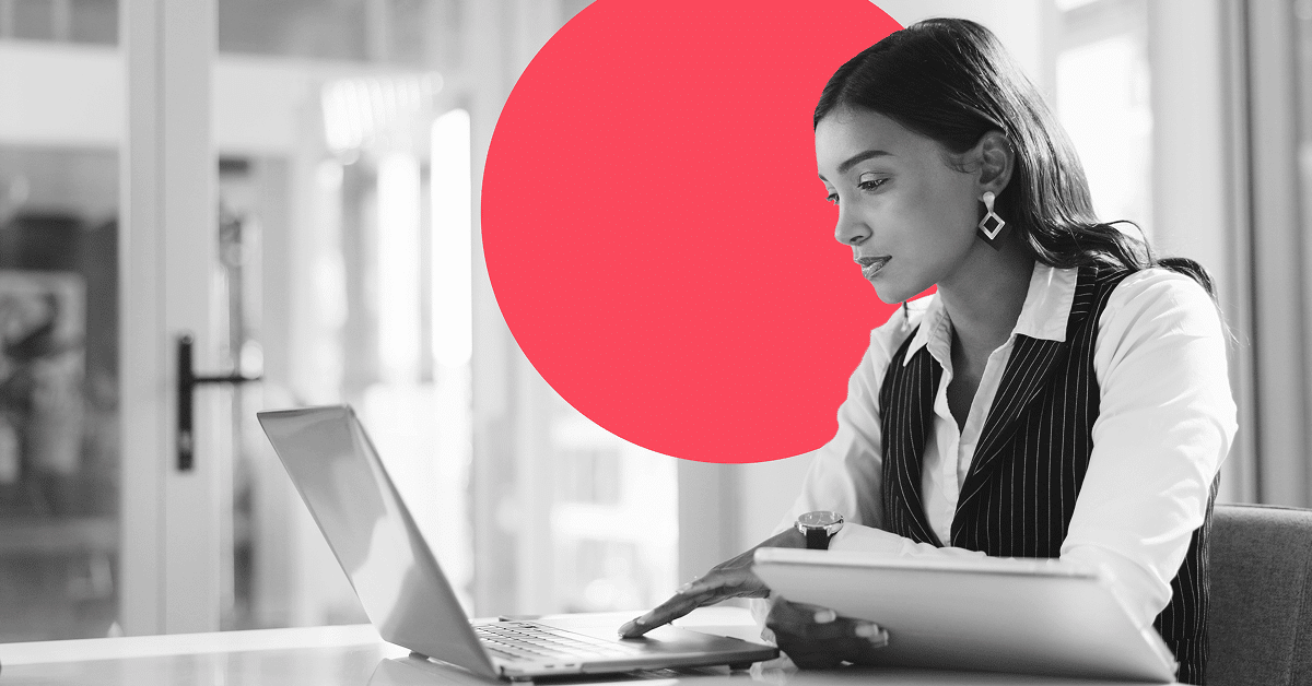 Financial services professional using a laptop and tablet at her desk.